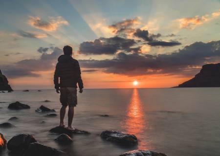 Hombre mirando como el paisaje se ilumina con la luz del amanecer