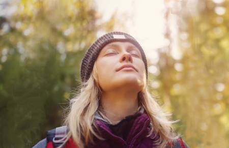 Mujer con los ojos cerrados disfrutando de estar en la naturaleza